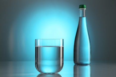 Photo of Fresh water in glass and bottle on mirror table against light blue gradient background. Backlit
