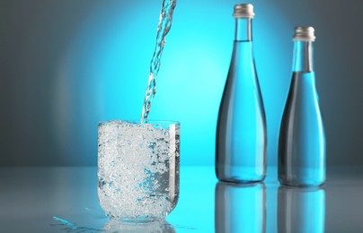 Photo of Pouring water into glass on mirror table against light blue gradient background. Backlit