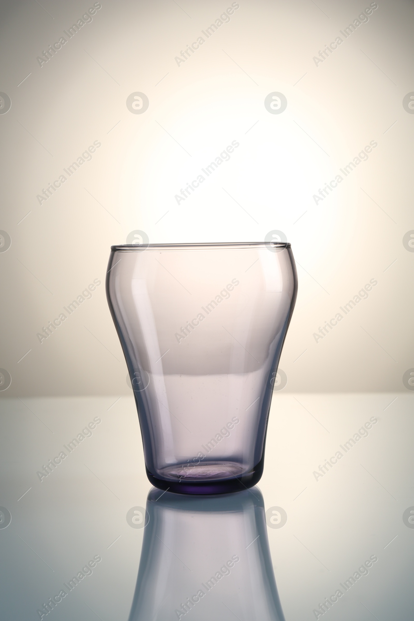 Empty clean glass on mirror table against gray gradient background Photo of Empty clean glass on mirror table against gray gradient background