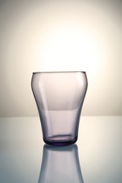 Photo of Empty clean glass on mirror table against gray gradient background