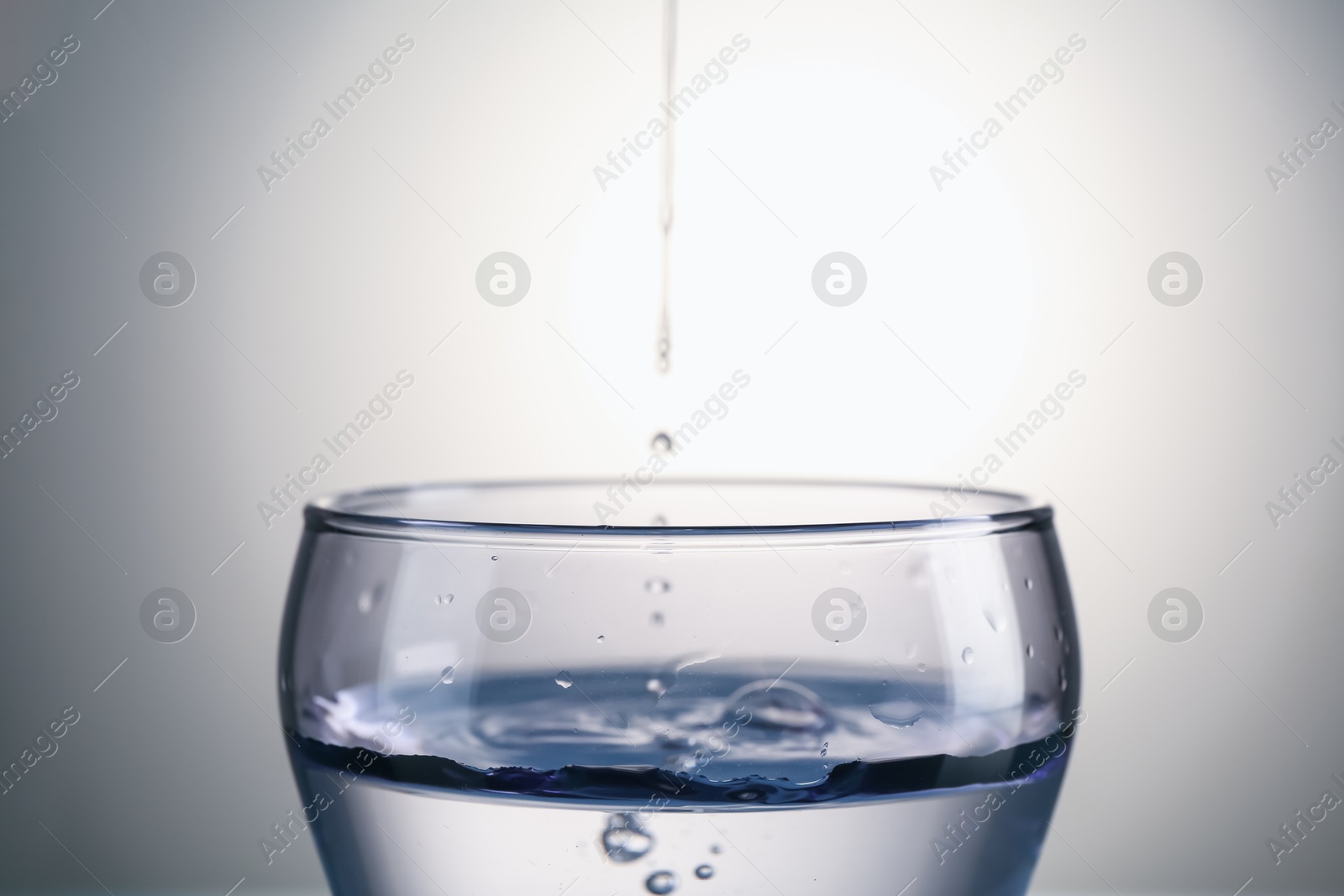 Fresh water in glass on gray gradient background, closeup Photo of Fresh water in glass on gray gradient background, closeup