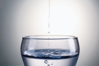 Photo of Fresh water in glass on gray gradient background, closeup
