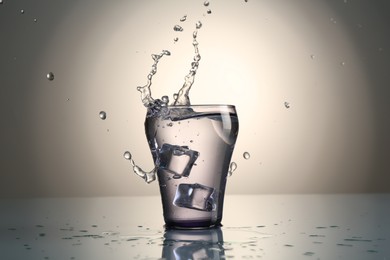 Photo of Fresh water splashing out of glass on mirror table against gray gradient background