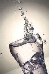 Photo of Fresh water splashing out of glass on gray gradient background, closeup