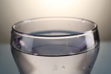 Photo of Fresh water in glass on gray gradient background, closeup