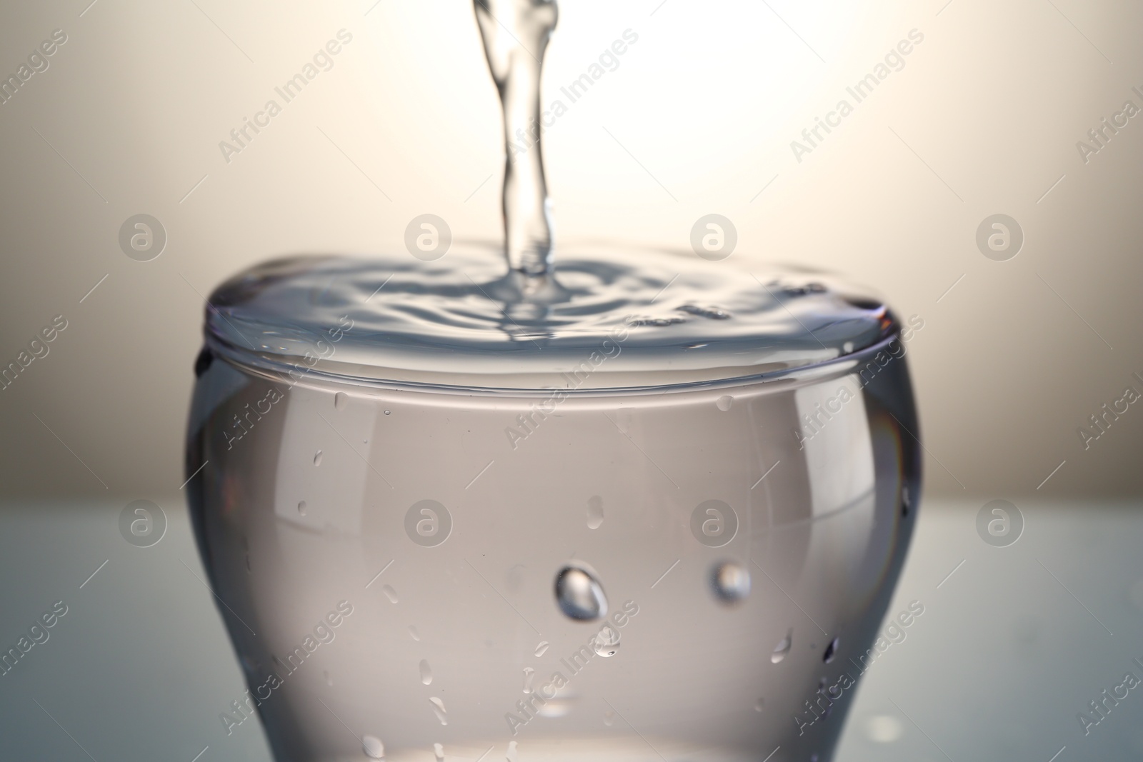 Pouring water into glass on gray gradient background, closeup Photo of Pouring water into glass on gray gradient background, closeup