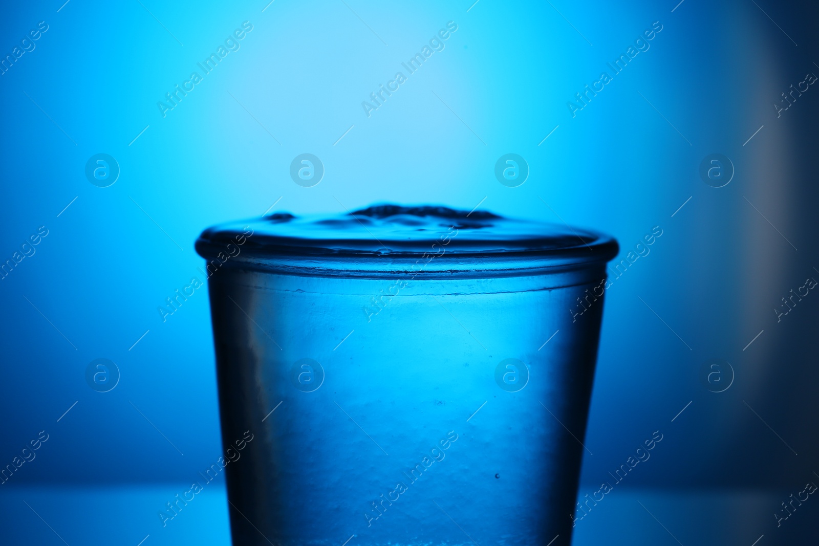 Fresh water in glass on blue gradient background, closeup. Backlit Photo of Fresh water in glass on blue gradient background, closeup. Backlit