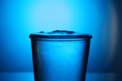 Photo of Fresh water in glass on blue gradient background, closeup. Backlit