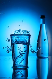 Photo of Fresh water splashing out of glass on blue gradient background. Backlit