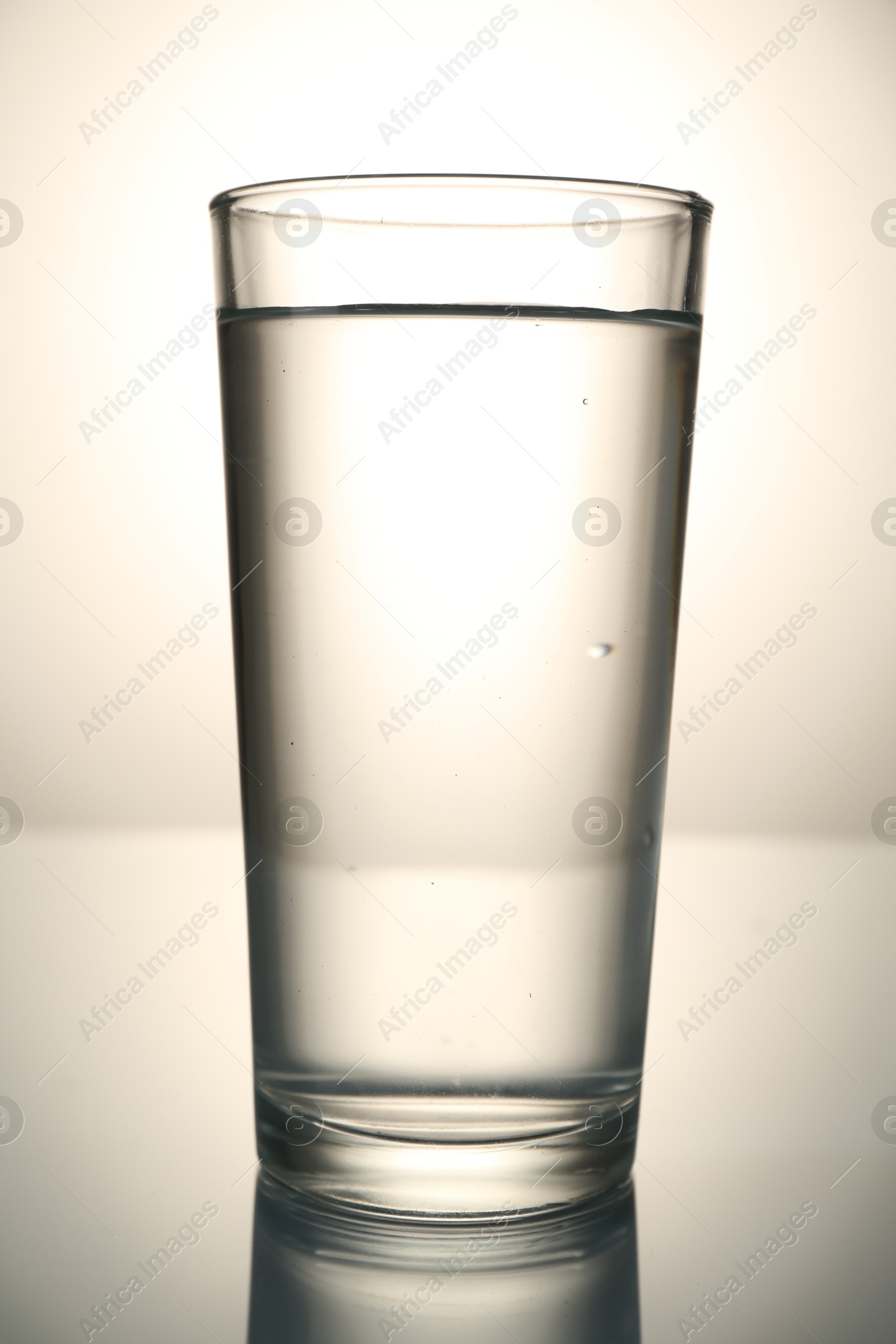 Fresh water in glass on mirror table against gray gradient background Photo of Fresh water in glass on mirror table against gray gradient background