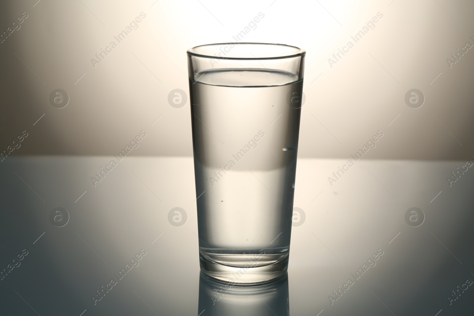 Fresh water in glass on mirror table against gray gradient background Photo of Fresh water in glass on mirror table against gray gradient background