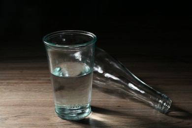Photo of Fresh water in glass and bottle on wooden table, closeup