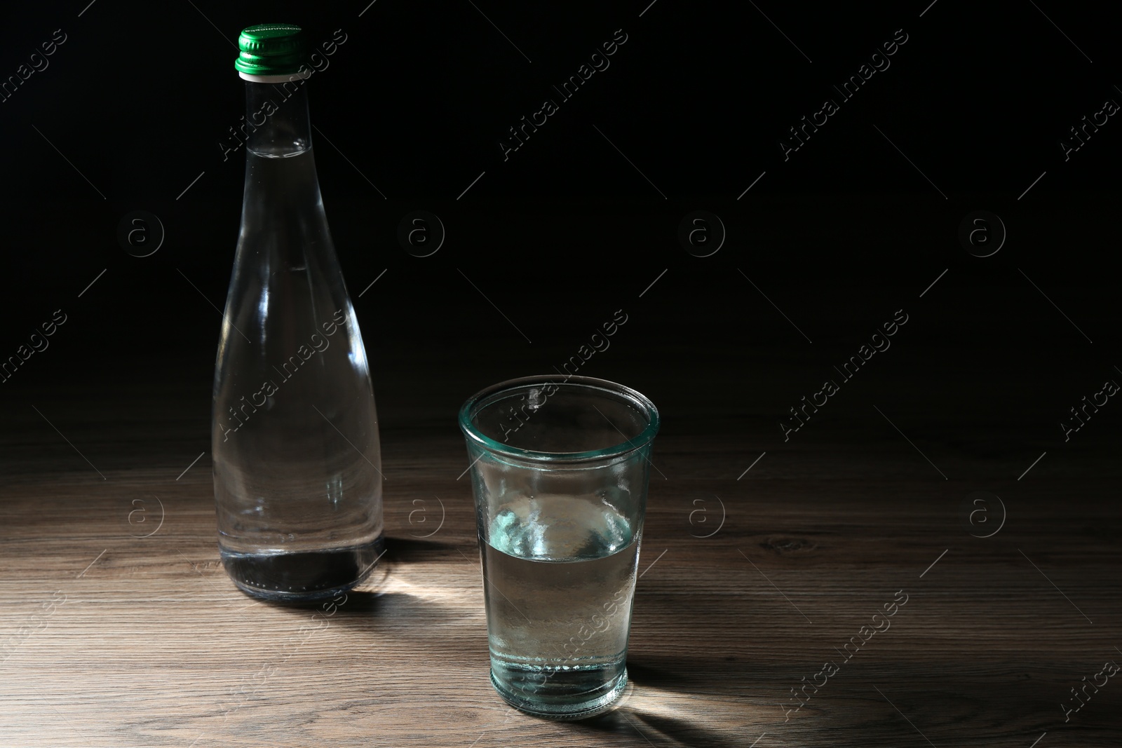 Fresh water in glass and bottle on wooden table Photo of Fresh water in glass and bottle on wooden table