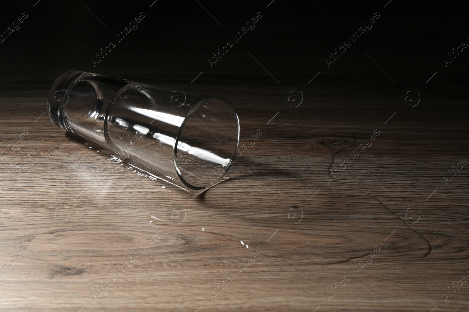 Photo of Overturned glass and spilled water on wooden table