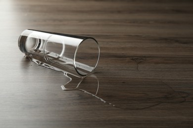 Photo of Overturned glass and spilled water on wooden table