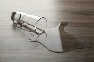Photo of Overturned glass and spilled water on wooden table
