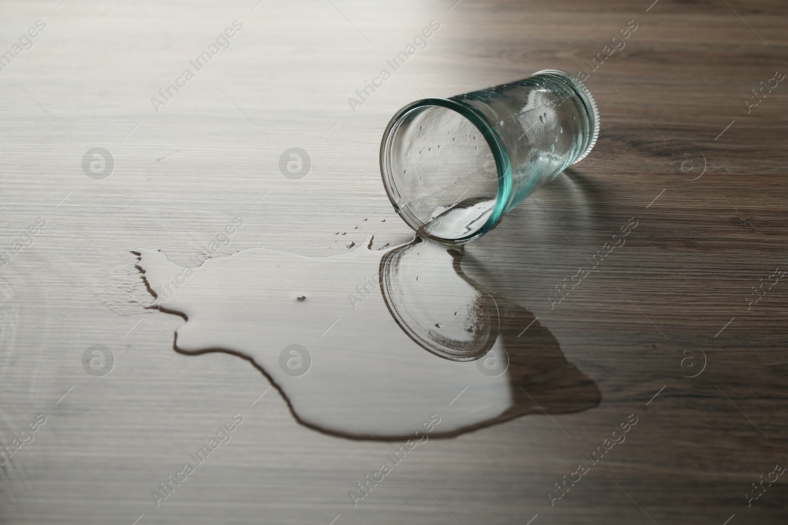 Photo of Overturned glass and spilled water on wooden table