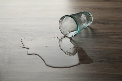 Photo of Overturned glass and spilled water on wooden table