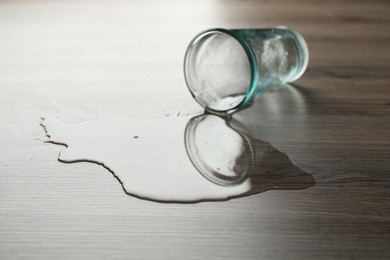 Photo of Overturned glass and spilled water on wooden table