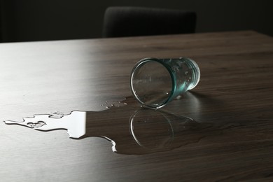 Photo of Overturned glass and spilled water on wooden table