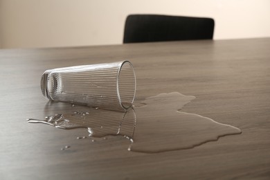 Photo of Overturned glass and spilled water on wooden table