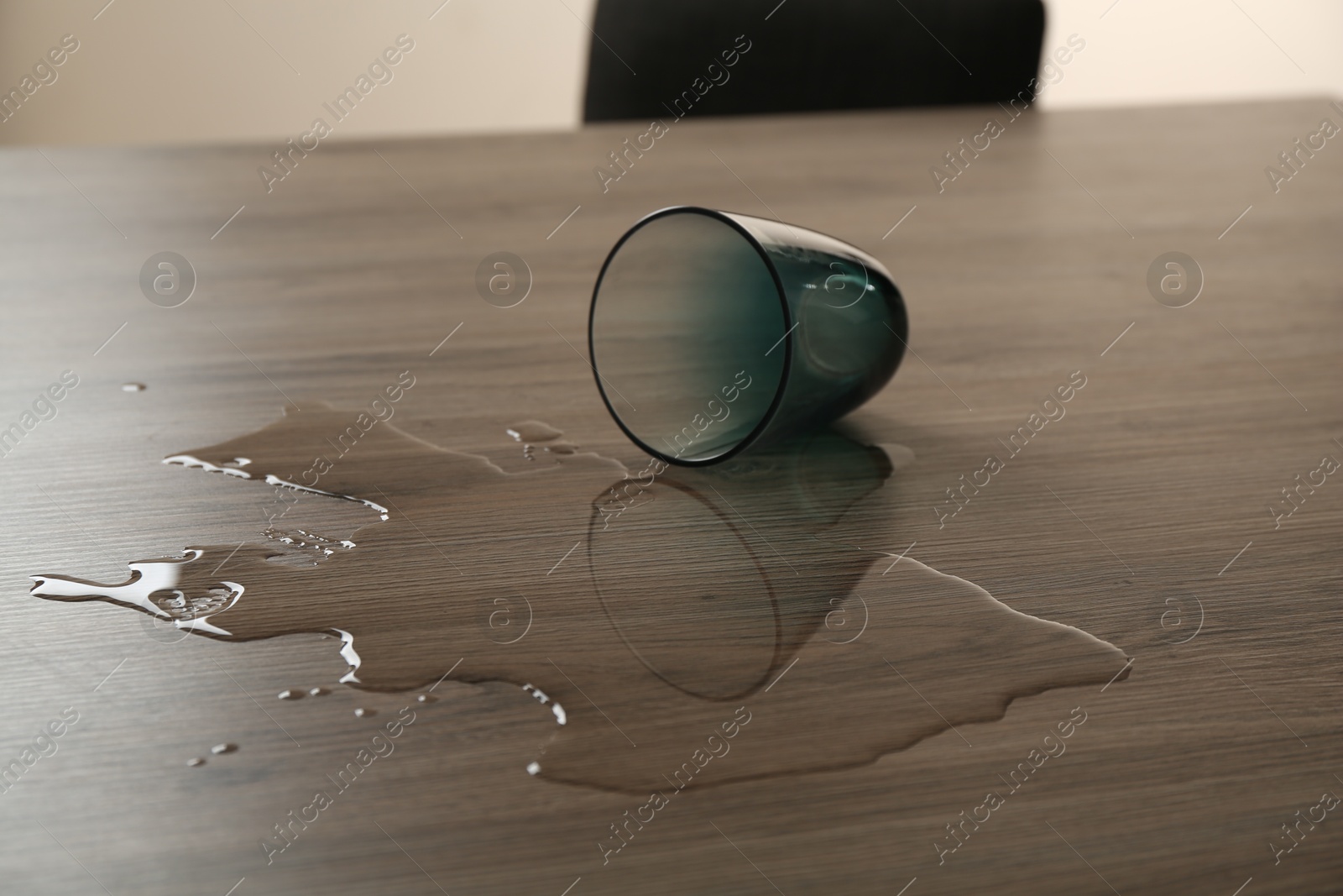 Photo of Overturned glass and spilled water on wooden table