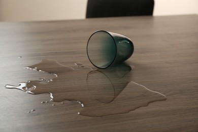 Photo of Overturned glass and spilled water on wooden table