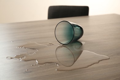 Photo of Overturned glass and spilled water on wooden table
