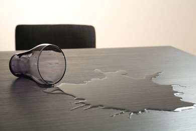 Photo of Overturned glass and spilled water on wooden table