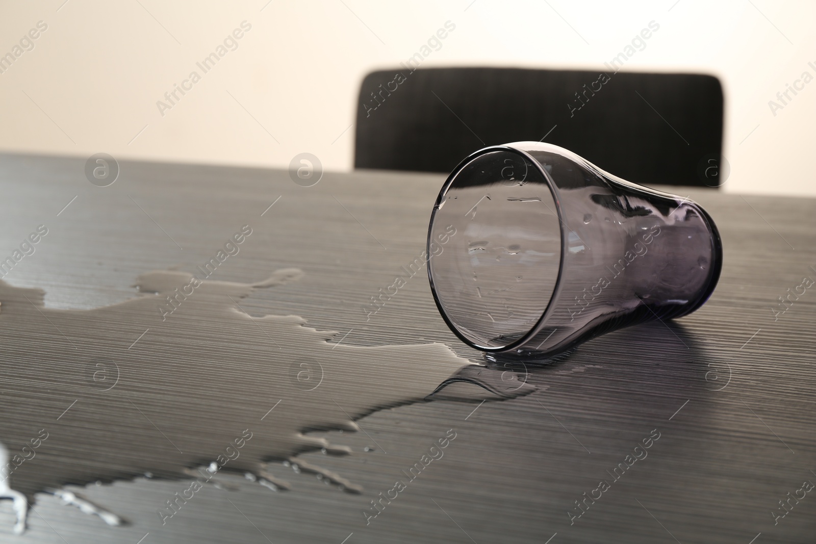 Overturned glass and spilled water on wooden table Photo of Overturned glass and spilled water on wooden table