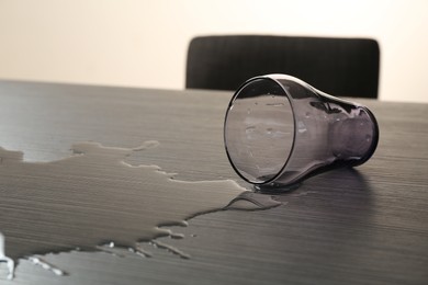 Photo of Overturned glass and spilled water on wooden table
