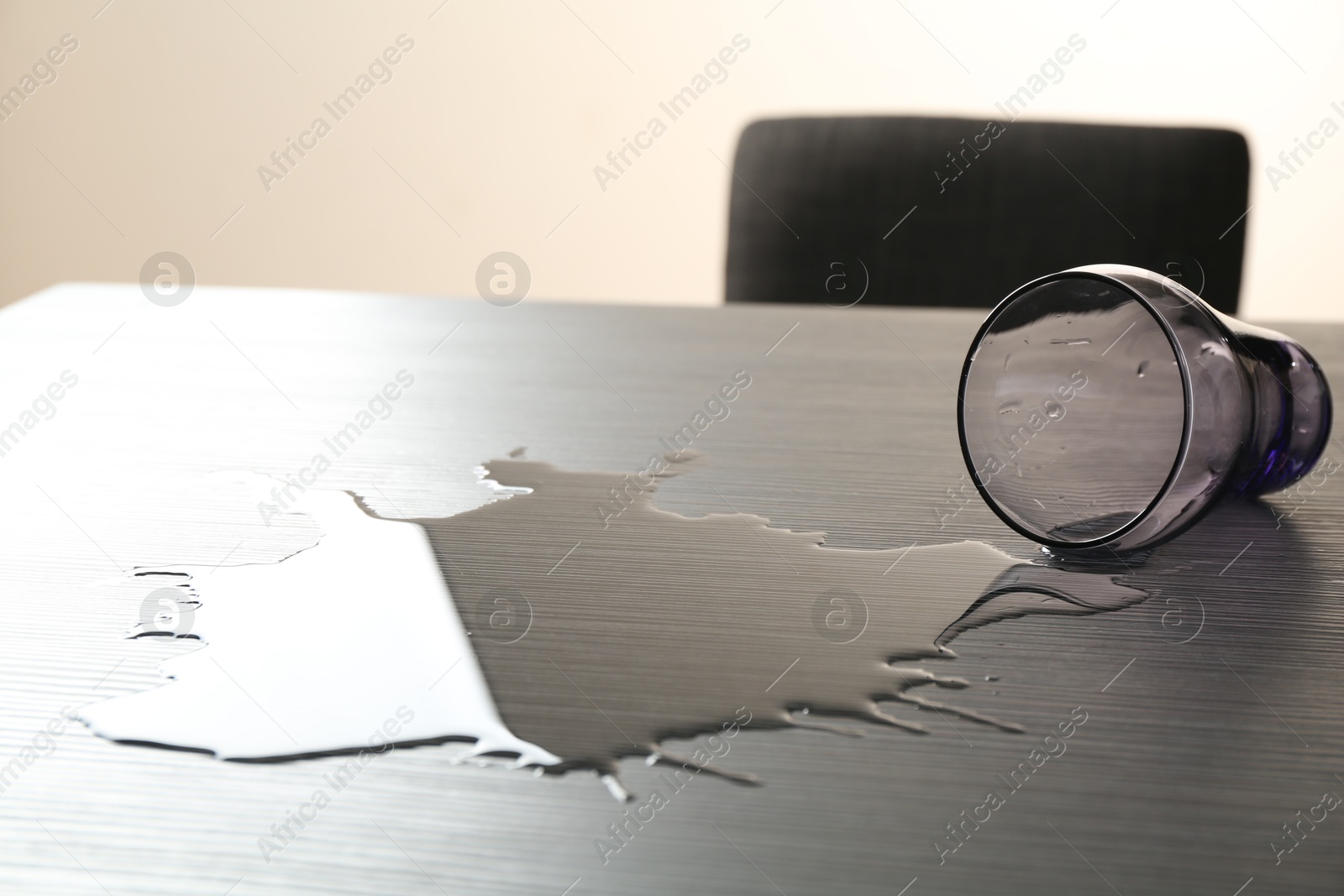 Photo of Overturned glass and spilled water on wooden table