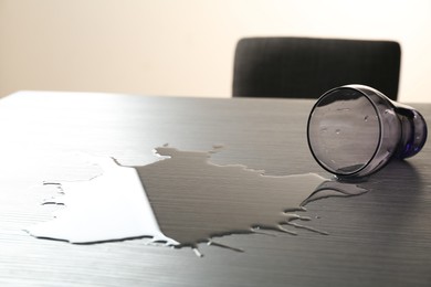 Photo of Overturned glass and spilled water on wooden table