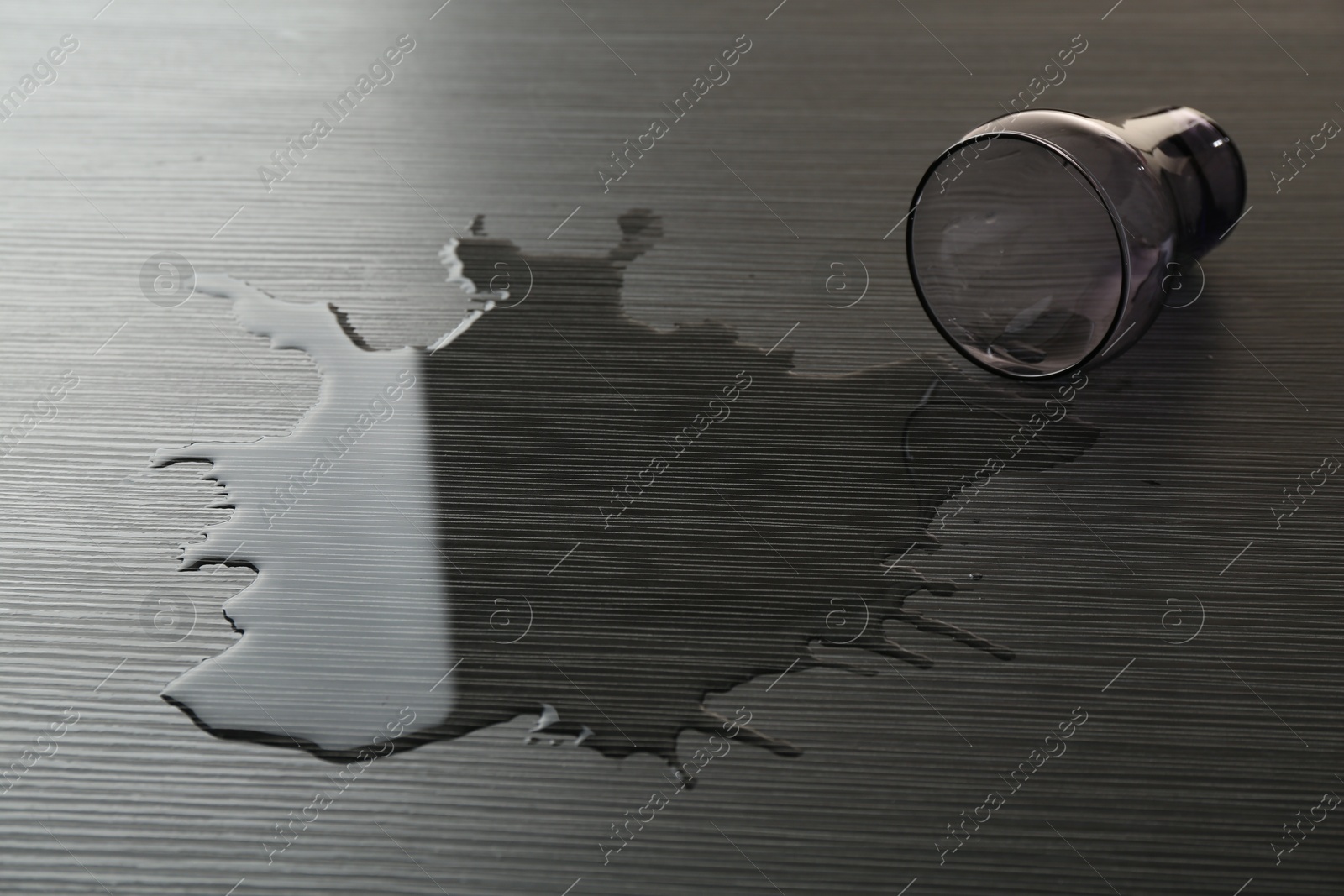 Photo of Overturned glass and spilled water on wooden table