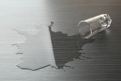 Photo of Overturned glass and spilled water on wooden table