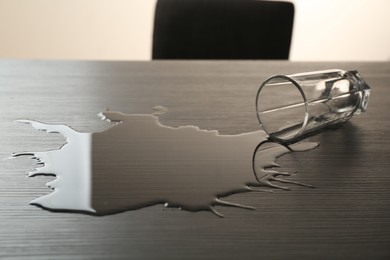 Photo of Overturned glass and spilled water on wooden table