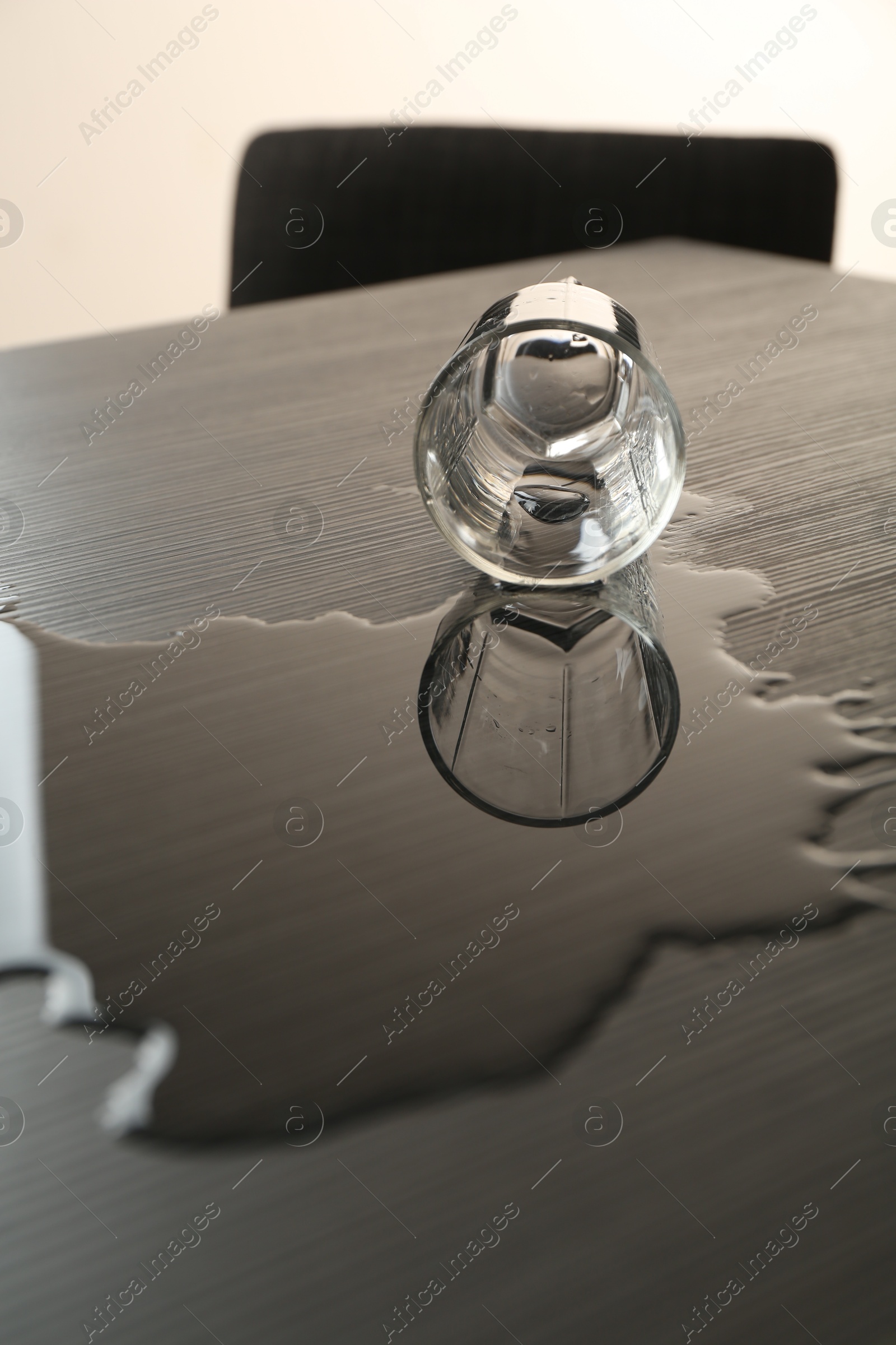 Overturned glass and spilled water on wooden table Photo of Overturned glass and spilled water on wooden table