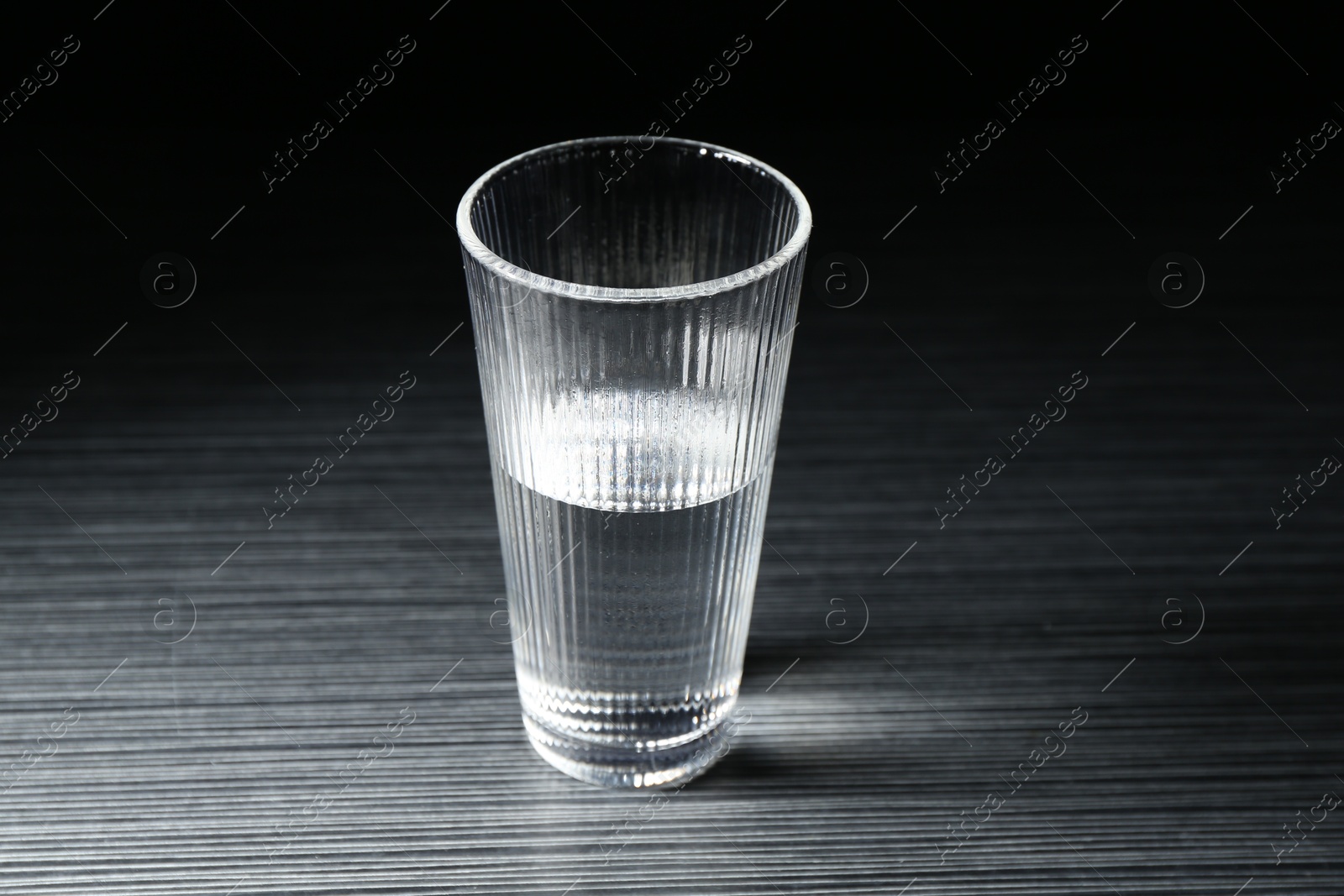 Fresh water in glass on dark wooden table Photo of Fresh water in glass on dark wooden table