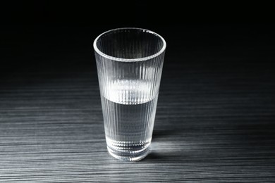 Photo of Fresh water in glass on dark wooden table