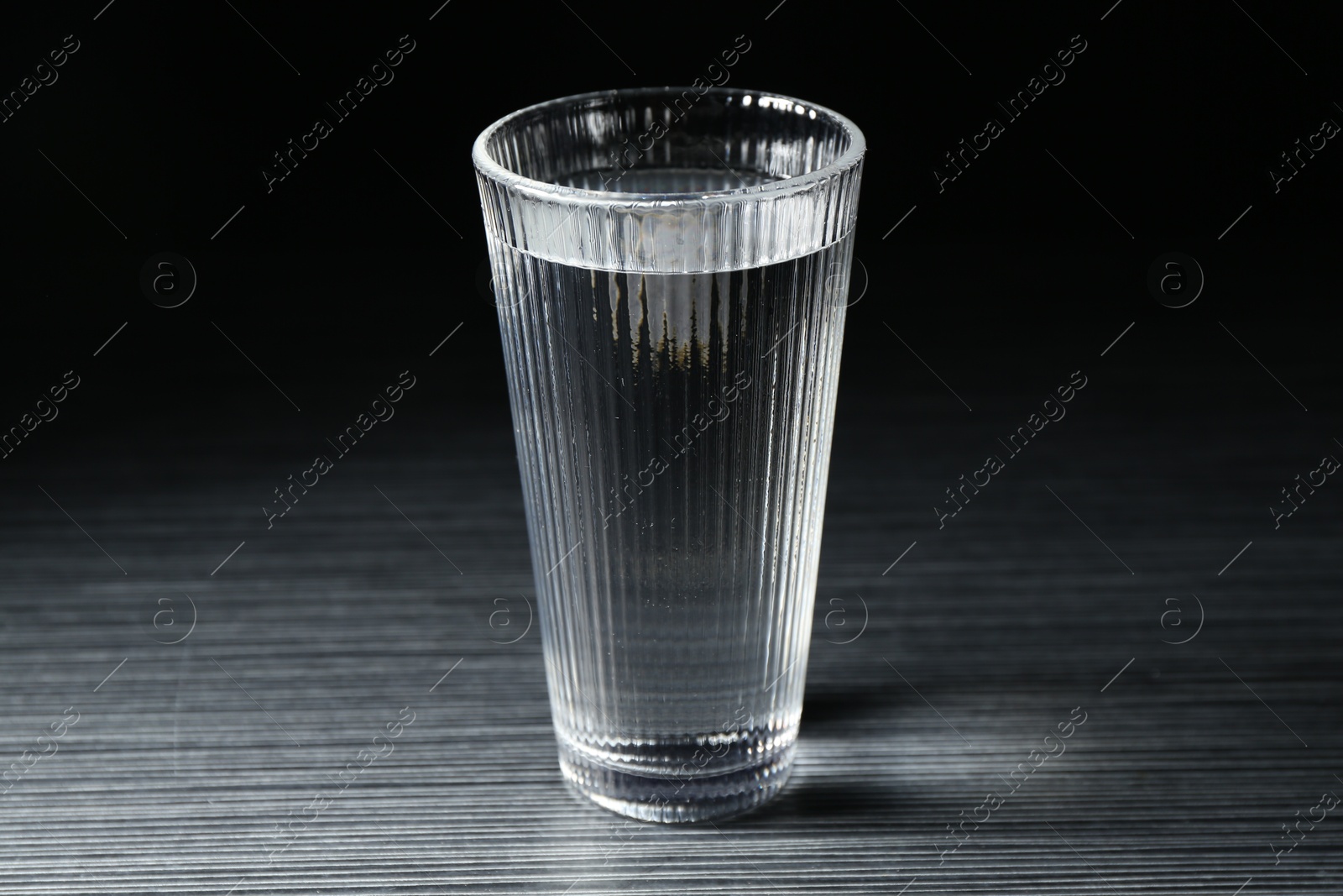 Fresh water in glass on dark wooden table Photo of Fresh water in glass on dark wooden table
