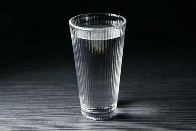 Photo of Fresh water in glass on dark wooden table