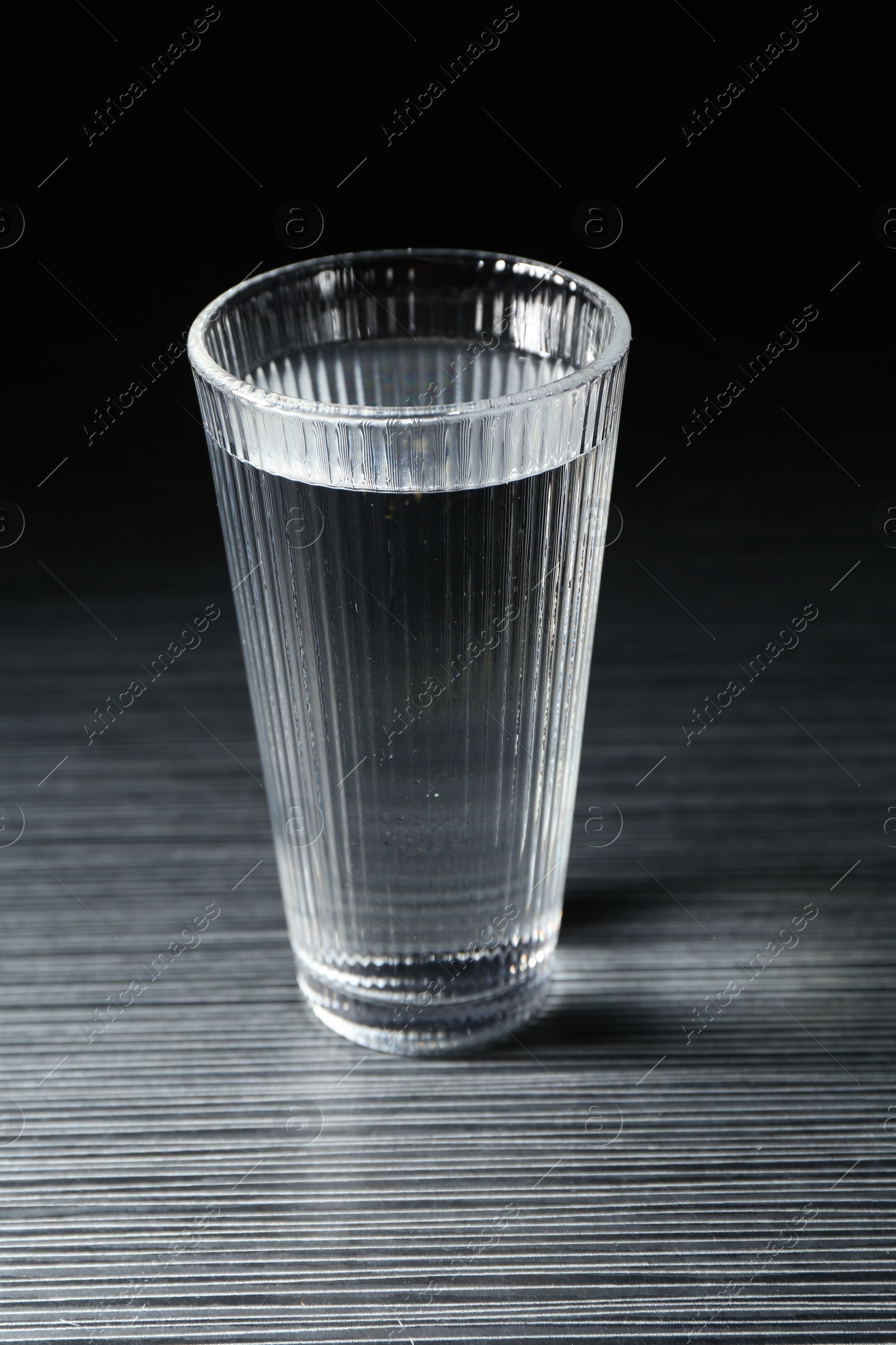 Fresh water in glass on dark wooden table Photo of Fresh water in glass on dark wooden table