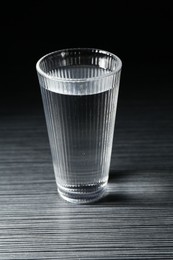 Photo of Fresh water in glass on dark wooden table
