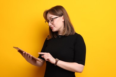 Photo of Woman with modern tablet on orange background