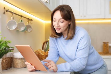Photo of Portrait of woman with modern tablet in kitchen