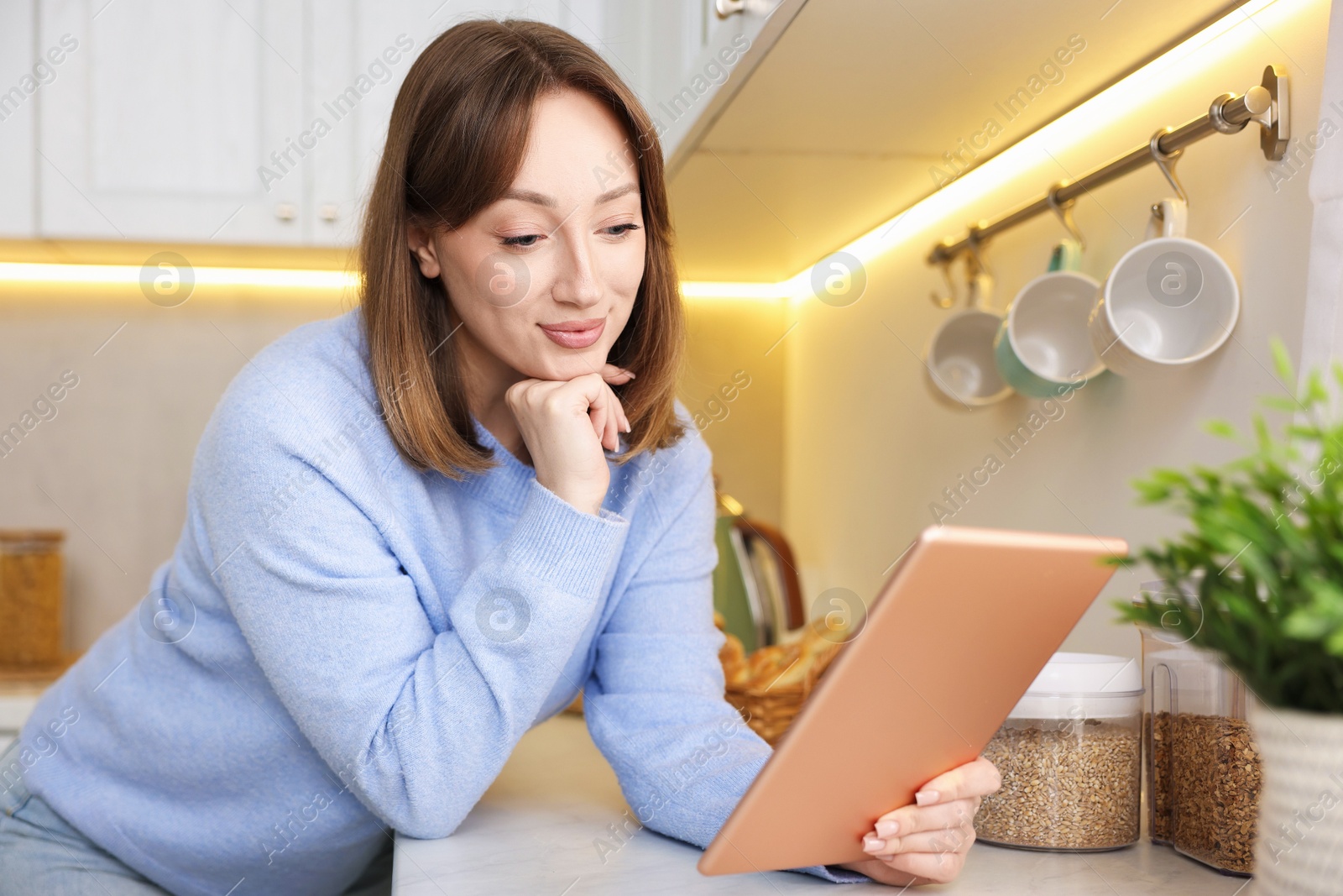 Photo of Portrait of woman with modern tablet in kitchen