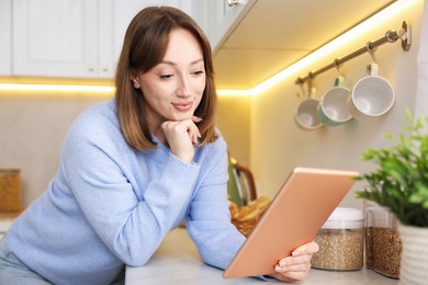 Photo of Portrait of woman with modern tablet in kitchen