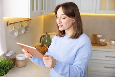 Photo of Portrait of woman with modern tablet in kitchen