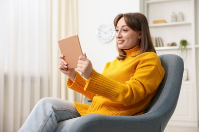 Photo of Woman with modern tablet in armchair at home