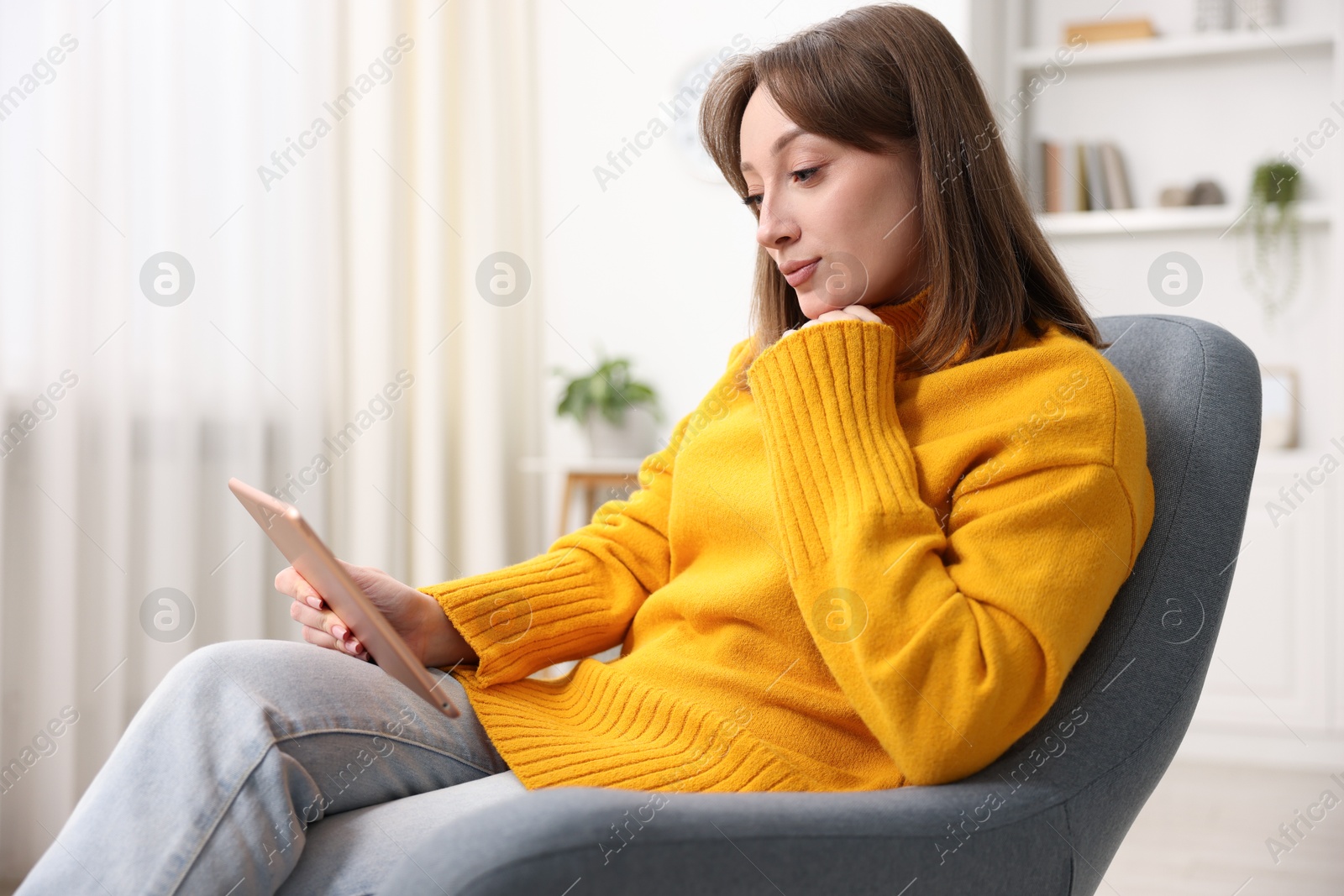 Photo of Woman with modern tablet in armchair at home
